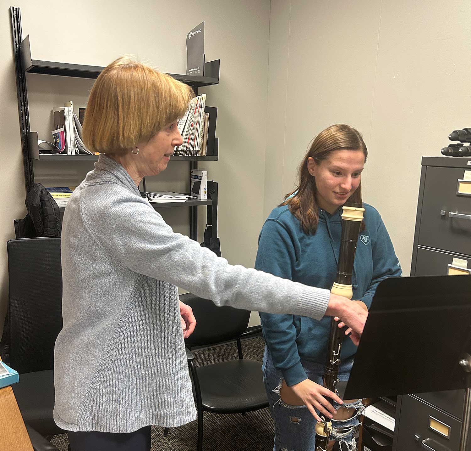 Person instructing a student on a woodwind instrument