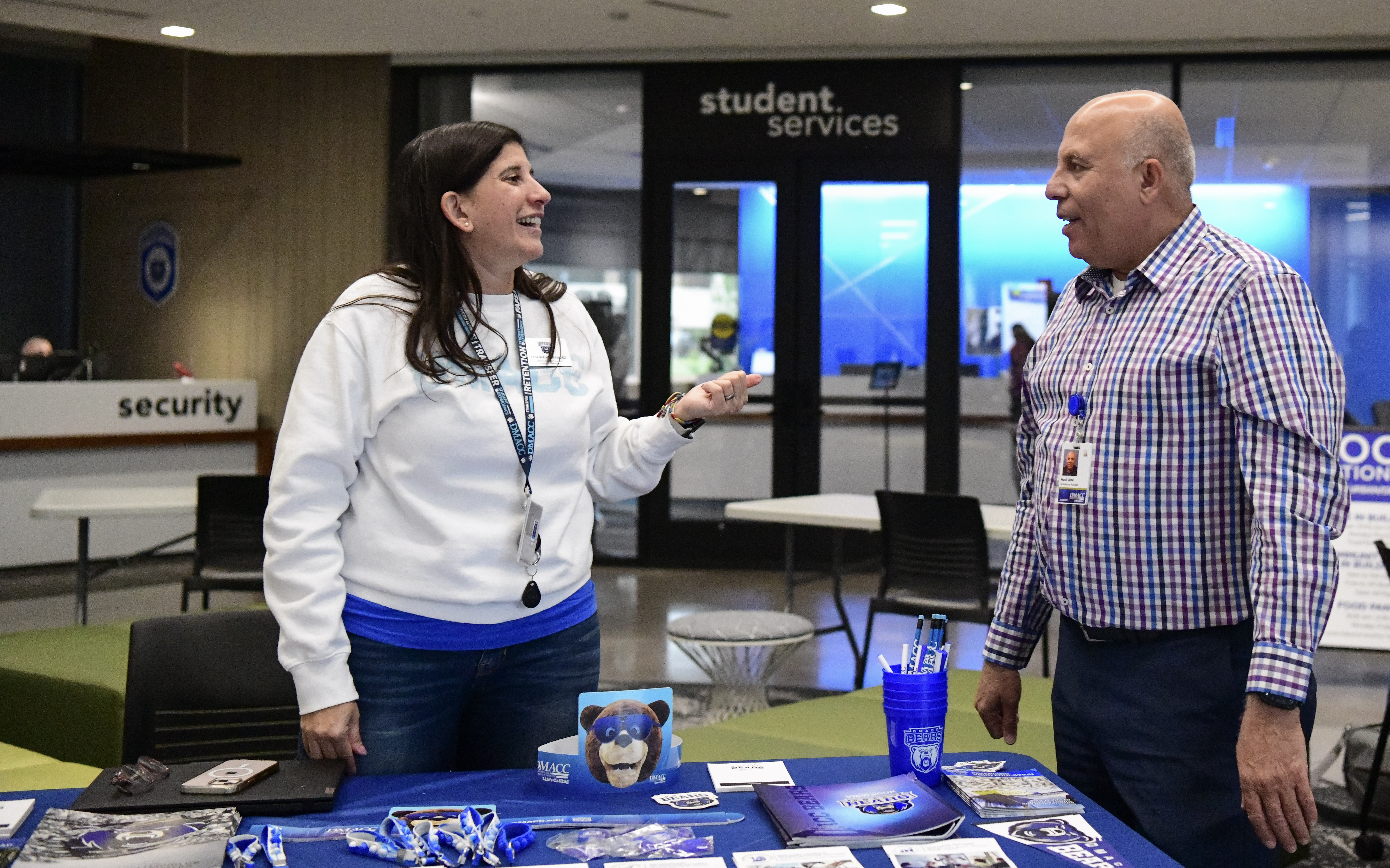 Two people stand at a table with promotional materials at an event