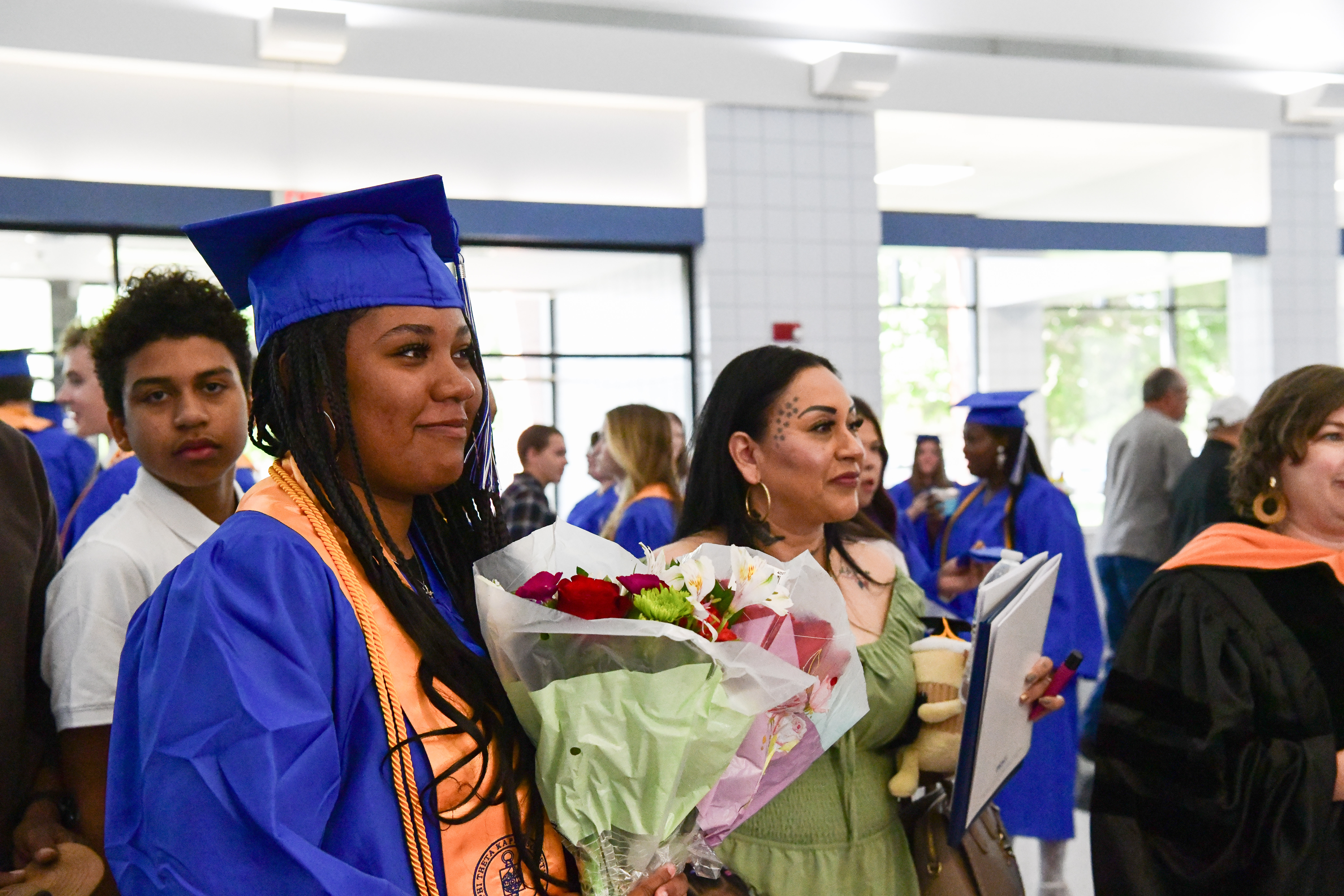 Anika Garcia Graduate in blue gown and cap holds bouquet of flowers