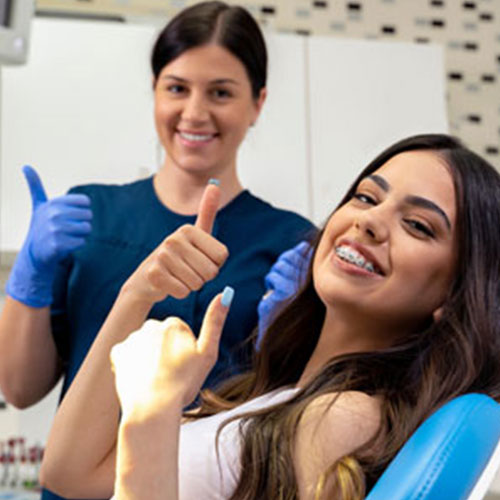 Hygienist and patient giving a thumbs up