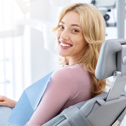 A woman in a dental chair looking over her shoulder and smiling